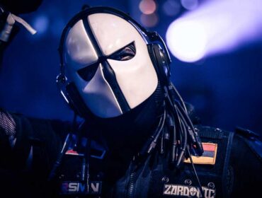 Zardonic on stage, mask head on, the Venezuelan flag on his arm