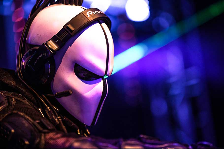 Zardonic in profile behind the decks, wearing headphones
